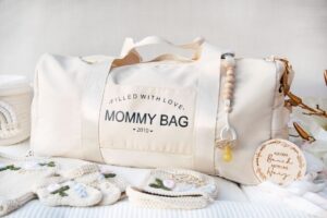 mommy bag in beige mit baby söckchen und Schnuller im Vordergrund